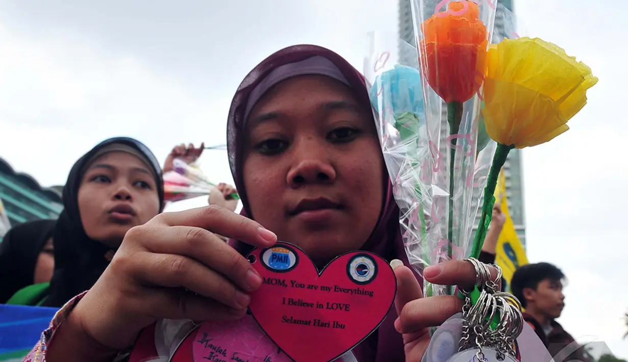 Seorang wanita memperlihatkan tanda cinta yang bertuliskan selamat hari ibu, Jakarta, Minggu (22/12/2014) (Liputan6.com/Johan Tallo)