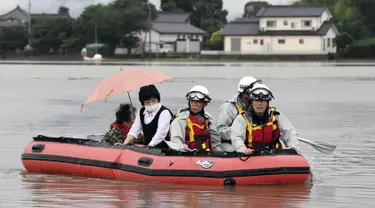 Warga dievakuasi menggunakan perahu karet saat banjir merendam daerah Asakura di prefektur Fukuoka, Kamis (6/7). Hujan lebat yang disebabkan angin topan di selatan Jepang telah memaksa evakuasi hampir 400.000 orang. (Sadayuki Goto/Kyodo News via AP)