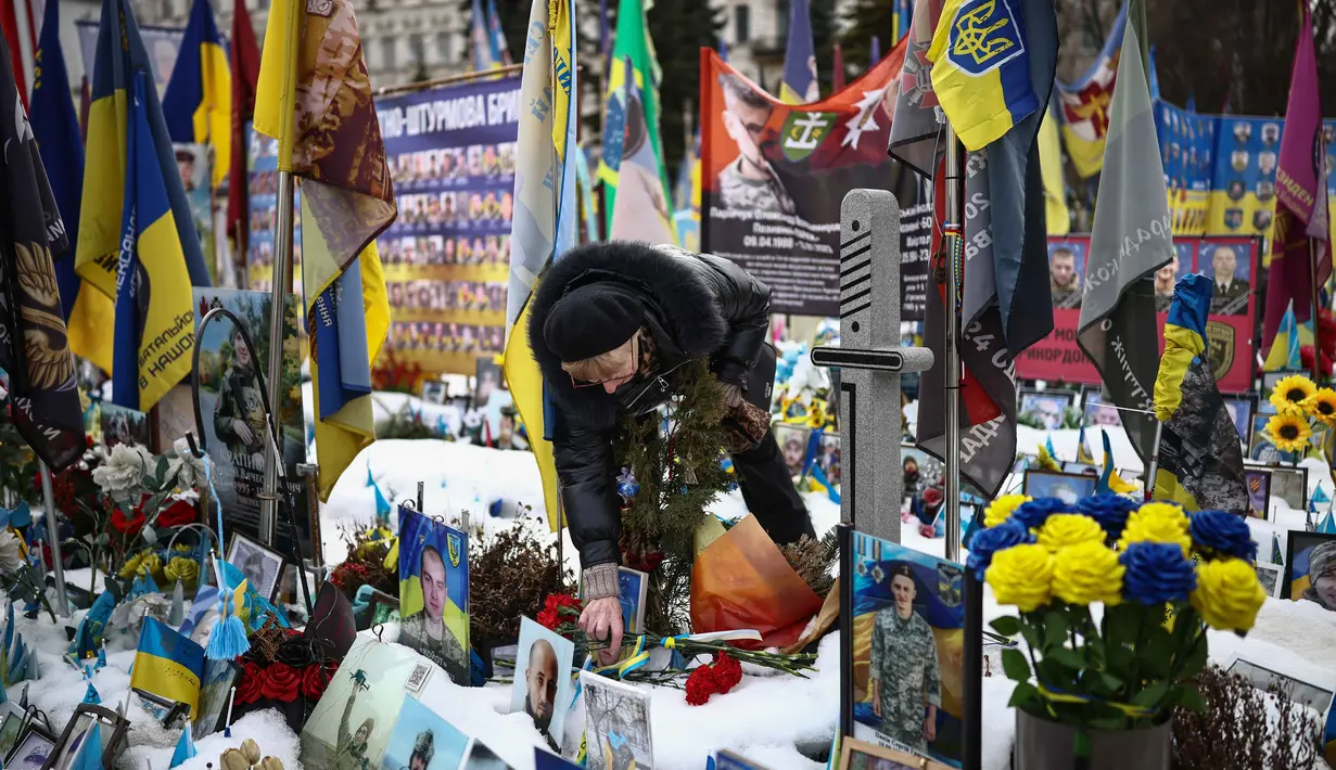 Dalam laporan terbarunya, Center for Strategic and International Studies (CSIS) memperkirakan, sekitar 1,8 juta tentara dari kedua belah pihak tewas, terluka, atau hilang sejak invasi skala penuh pada 24 Februari 2022. Tampak dalam foto, seorang warga setempat mengunjungi tugu peringatan sementara untuk tentara Ukraina dan asing di Lapangan Kemerdekaan, Kyiv, saat peringatan keempat invasi Rusia ke Ukraina, Selasa 24 Februari 2026. (HENRY NICHOLLS/AFP)