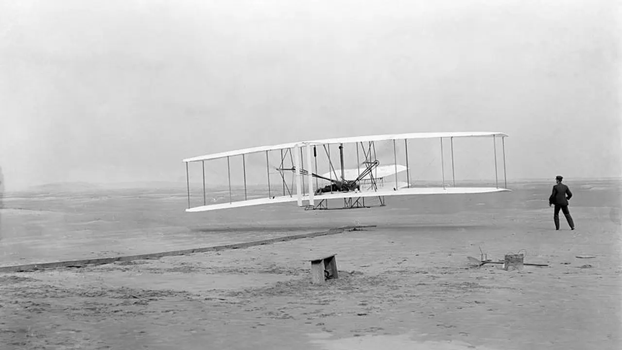 Penerbangan pertama Wright Bersaudara. Orville yang mengendalikan pesawat, sedangkan Wilbur tampak berlari di samping setelah melepaskan pegangannya untuk menyeimbangkan pesawat itu. (Wikimedia Commons)