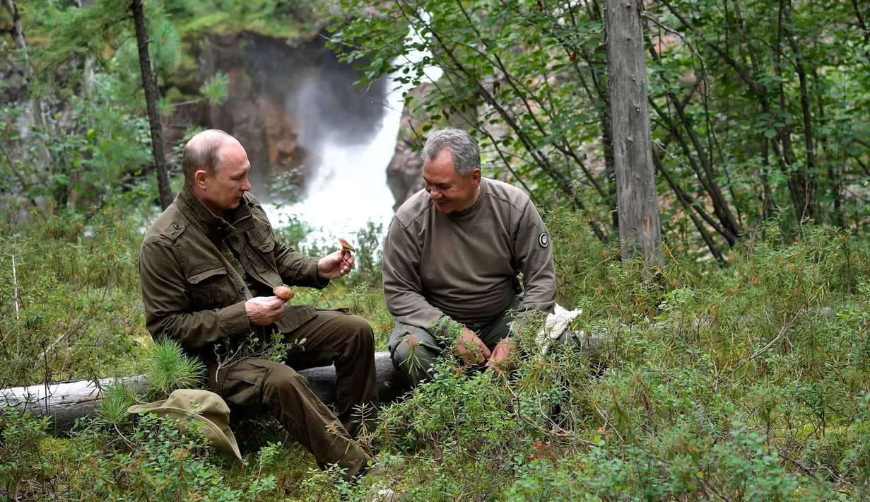 Presiden Rusia Vladimir Putin dan Menteri Pertahanan Sergei Shoigu beristirahat setelah memancing selama liburan mini di wilayah Siberia Tyva. Foto dirilis biro pers Kremlin, pada 5 Agustus 2017. (Alexei Nikolsky / Sputnik, Foto Kolam Kremlin via AP)