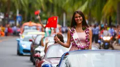 Kontestan Miss World dari Moldova tersenyum sambil membawa bendera China saat mengikuti pawai menggunakan supercar di Sanya, Provinsi Hainan, China, (7/11). Pawai ini membuka kontes kecantikan Miss World ke-67. (AFP Photo/Str/China Out)