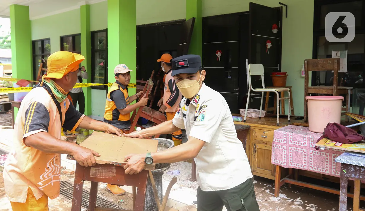 Petugas memindahkan meja dan kursi saat membersihkan ruangan di MTsN 19 Pondok Labu, Jakarta, Jumat (7/10/2022). Petugas PPSU, Satpol PP, dan Dinas Pemadam Kebakaran membersihkan ruang kelas, kantin, dan fasilitas lainnya usai terendam banjir pada Kamis sore kemarin. (Liputan6.com/Herman Zakharia)