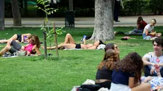 Orang-orang beristirahat di rumput di taman Retiro di Madrid tengah, Spanyol pada 25 April 2023. (AFP/Thomas Coex)