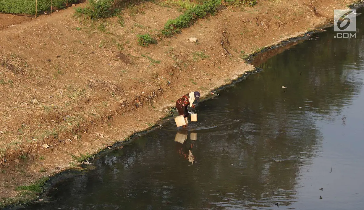 Warga mengambil air di aliran Kanal Banjir Timur yang surut di Jakarta, Selasa (9/10). Berkurangnya debit air akibat musim kemarau menyebabkan sampah yang mengendap di kanal pengendali banjir tersebut tampak ke permukaan. (Liputan6.com/Immanuel Antonius)