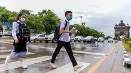 Sejumlah siswa yang mengenakan masker menyeberangi jalan saat pulang sekolah di Vientiane, Laos, Selasa (19/5/2020). Pemerintah Laos telah mengumumkan bahwa semua siswa di negara itu dapat kembali bersekolah mulai 2 Juni mendatang. (Xinhua/Kaikeo Saiyasane)