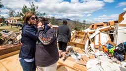 Seorang wanita memeluk keluarganya saat berada di puing-puing rumah mereka yang rusak usai diterjang badai di Elon, Virginia (16/4). Akibat badai ini sejumlah rumah rusak berat. (Jay Westcott/The News & Advance via AP)