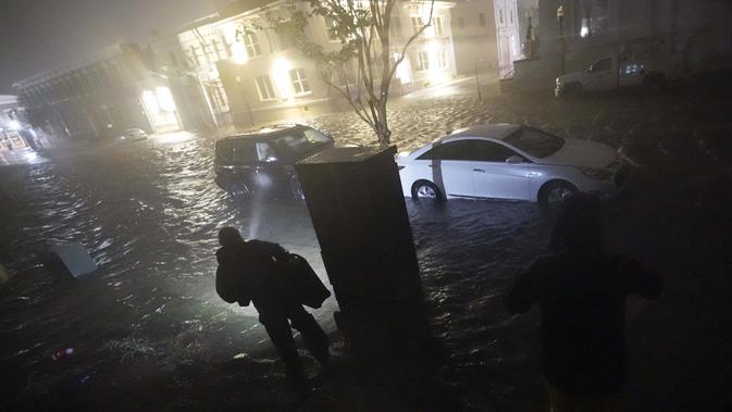 Orang-orang menggunakan senter saat mereka berjalan di jalan-jalan yang banjir untuk mencari kendaraan mereka di Pensacola, Florida, Rabu (16/9/2020). Badai Sally membuat pendaratan hari Rabu di dekat Gulf Shores, Alabama, sebagai badai Kategori 2. (AP Photo/Gerald Herbert)