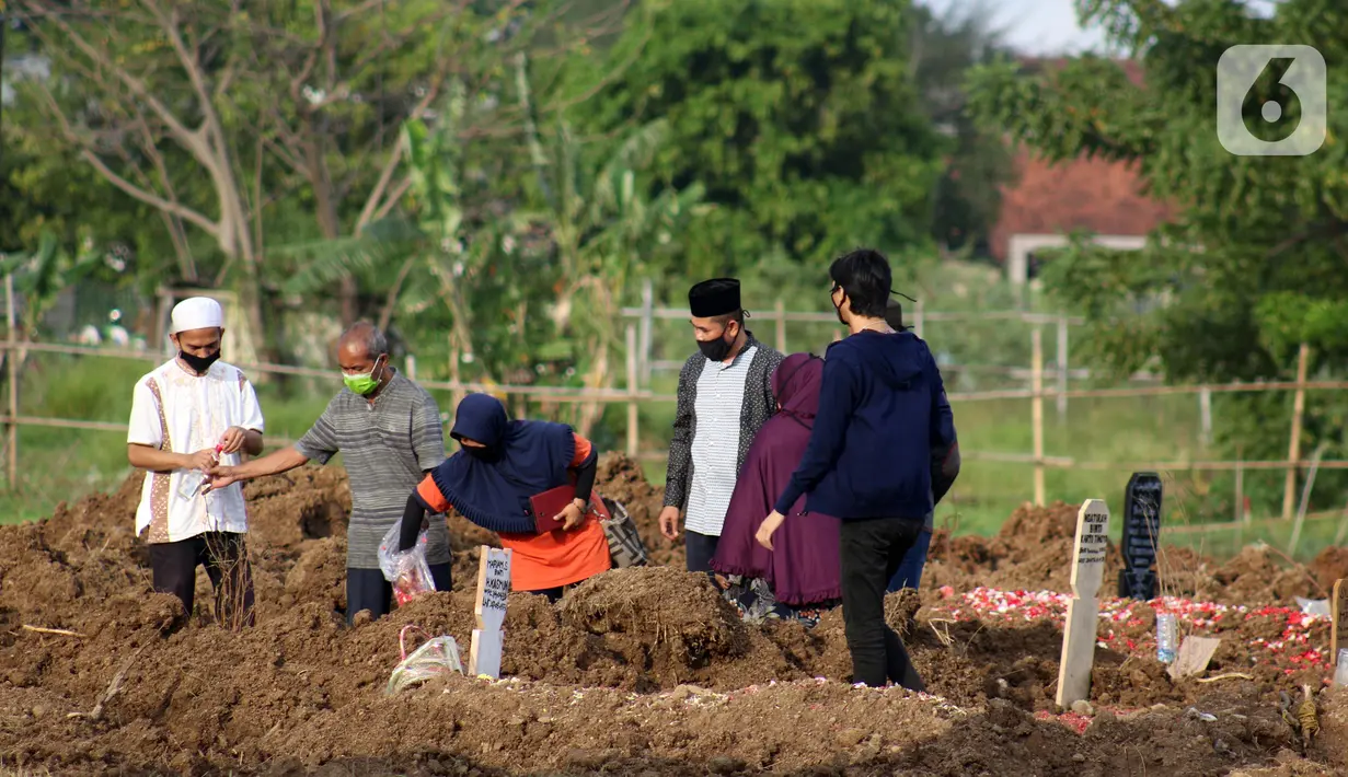 Para kerabat berdoa usai pemakaman pasien Covid-19 di TPU Tegal Alur, Jakarta, Rabu (15/4/2020). Pemprov DKI Jakarta menyediakan dua TPU yang dijadikan lokasi pemakaman pasien meninggal akibat Covid-19, yakni TPU Pondok Ranggon dan Tegal Alur. (Liputan6.com/Helmi Fithriansyah)