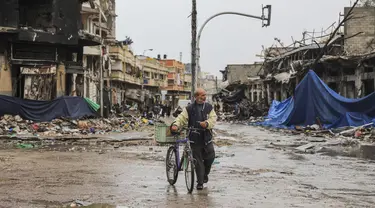 Seorang warga Palestina berjalan di Kota Gaza pada hari keempat gencatan senjata sementara antara Hamas dan Israel, Senin (27/11/2023). (AP Photo/Mohammed Hajjar)