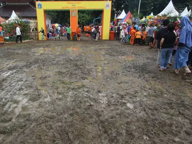 Pengunjung menghindari jalan tanah yang becek pada Festival Lebaran Betawi IX di Lapangan Banteng, Jakarta, Minggu (14/8). Meskipun becek akibat hujan, namun warga tetap antusias mengunjungi festival tahunan tersebut. (Liputan6.com/Immanuel Antonius)