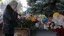 Seorang wanita menangis saat melewati mainan dan bunga untuk korban jatuhnya pesawat maskapai Flydubai, di luar Bandara Rostov-on-Don, Rusia, Minggu (20/3). Insiden itu menewaskan seluruh penumpang dan kru yang berjumlah 62 orang. (REUTERS/Maxim Shemetov)