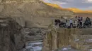 Warga Israel menyaksikan banjir bandang terjadi menyusul hujan lebat di gurun Negev di sebelah timur kota Dimona Israel pada 26 Desember 2022. Hujan lebat mengguyur Israel pada hari Senin (26/12) membanjiri jalan-jalan kota, memicu banjir bandang di dasar sungai gurun yang kering dan membasahi daerah pedesaan karena suhu turun ke level terendah musim ini. (AFP/Menahem Kahana)