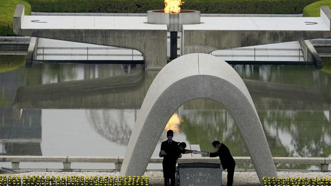 Walikota Hiroshima, Kazumi Matsui (kanan) dan keluarga busur yang telah meninggal sebelum mereka menempatkan daftar korban Bom Atom di Hiroshima Memorial Cenotaph selama upacara peringatan 75 tahun pemboman di Taman Peringatan Perdamaian Hiroshima, Jepang (4/8/2020). (AP Photo/Eugene Hoshiko)