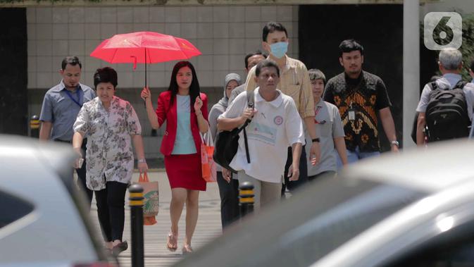 Seorang wanita menggunakan payung menyebrang selama gelombang panas di Jakarta, Selasa (22/10/2019).  BMKG memprediksi wilayah Indonesia akan mengalami panas selama kurang lebih satu minggu ini. Hal ini dikarenakan matahari yang berada dekat dengan jalur khatulistiwa. (Liputan6.com/Faizal Fanani)