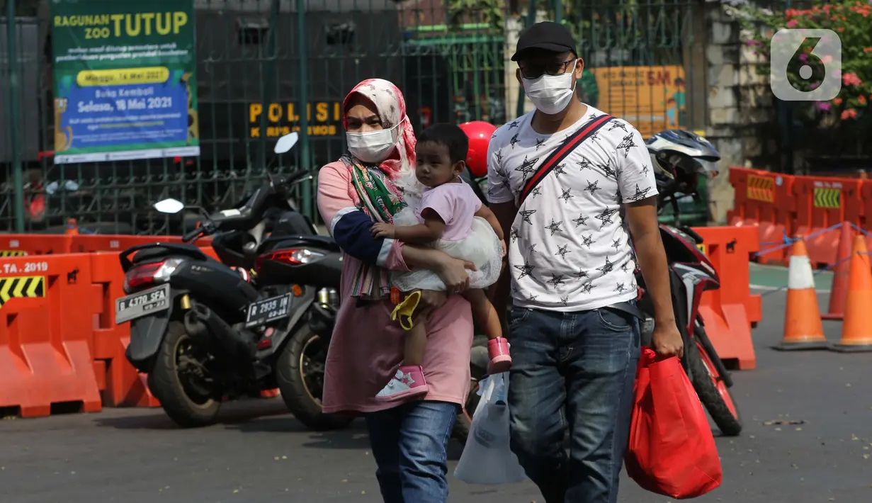 Calon pengunjung melintas di depan gerbang utama kawasan Kebun Binatang Ragunan, Jakarta, Minggu (16/5/2021). Sejumlah kawasan wisata di DKI Jakarta ditutup sementara untuk umum hingga 18 Mei 2021 untuk pemberlakukan penguatan protokol kesehatan COVID-19. (Liputan6.com/Helmi Fithriansyah)