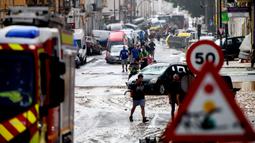 Warga berjalan di samping tumpukan mobil di sebuah jalan yang tertutup lumpur setelah banjir di kawasan De La Torre, Valencia, Spanyol timur, pada tanggal 30 Oktober 2024. (Ruben FENOLLOSA/AFP)