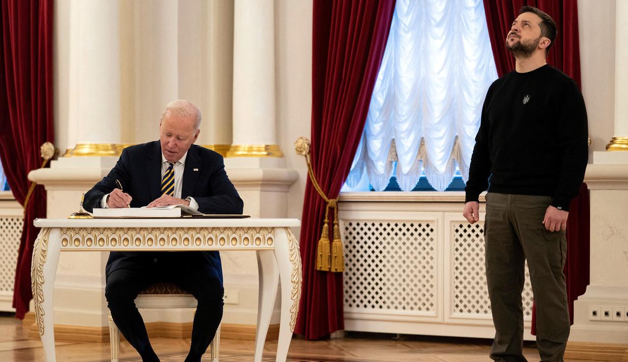 Presiden Joe Biden (kiri) menandatangani buku tamu dalam pertemuan dengan Presiden Ukraina Volodymyr Zelensky di Istana Mariinsky, Kyiv, Ukraina pada 20 Februari 2023. Presiden AS Joe Biden melakukan kunjungan mendadak ke Kyiv menjelang peringatan satu tahun invasi Rusia ke Ukraina. Biden bertemu dengan Presiden Ukraina Volodymyr Zelensky di ibu kota Ukraina dalam kunjungan pertamanya ke negara itu sejak dimulainya konflik. (Evan Vucci/POOL/AFP)