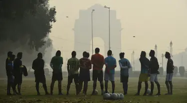 Sejumlah pria mendengarkan pelatih sebelum bermain sepak bola di tengah kondisi kabut asap tebal di New Delhi, India (30/10). Tingkat kabut melonjak selama musim dingin di Delhi, ketika kualitas udara memburuk. (AFP Photo/Prakash Singh)