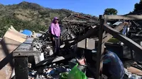 Seorang perempuan mencari sisa-sisa puing dari bangunan rumah yang rusak di Menggala, Lombok Utara, Rabu (8/8). Laporan terakhir mengatakan, gempa Lombok telah memakan 105 korban jiwa, dan lebih 70.000 orang kehilangan tempat tinggal. (AFP/ADEK BERRY)