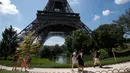 Turis berjalan melewati Menara Eiffel di Paris, Kamis (2/8). Wisatawan harus menelan kekecewaan karena mereka tak bisa masuk ke lokasi wisata yang menjadi ikon Prancis itu. (AP Photo/Michel Euler)