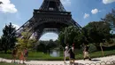 Turis berjalan melewati Menara Eiffel di Paris, Kamis (2/8). Wisatawan harus menelan kekecewaan karena mereka tak bisa masuk ke lokasi wisata yang menjadi ikon Prancis itu. (AP Photo/Michel Euler)