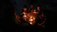 Sebuah keluarga Palestina menikmati makan sahur selama pemadaman listrik di kamp pengungsian Rafah, Jalur Gaza selatan, 11 Juni 2017. Israel mengumumkan pihaknya mengurangi pasokan listriknya ke Gaza atas permintaan Otoritas Palestina. (SAID KHATIB/AFP)