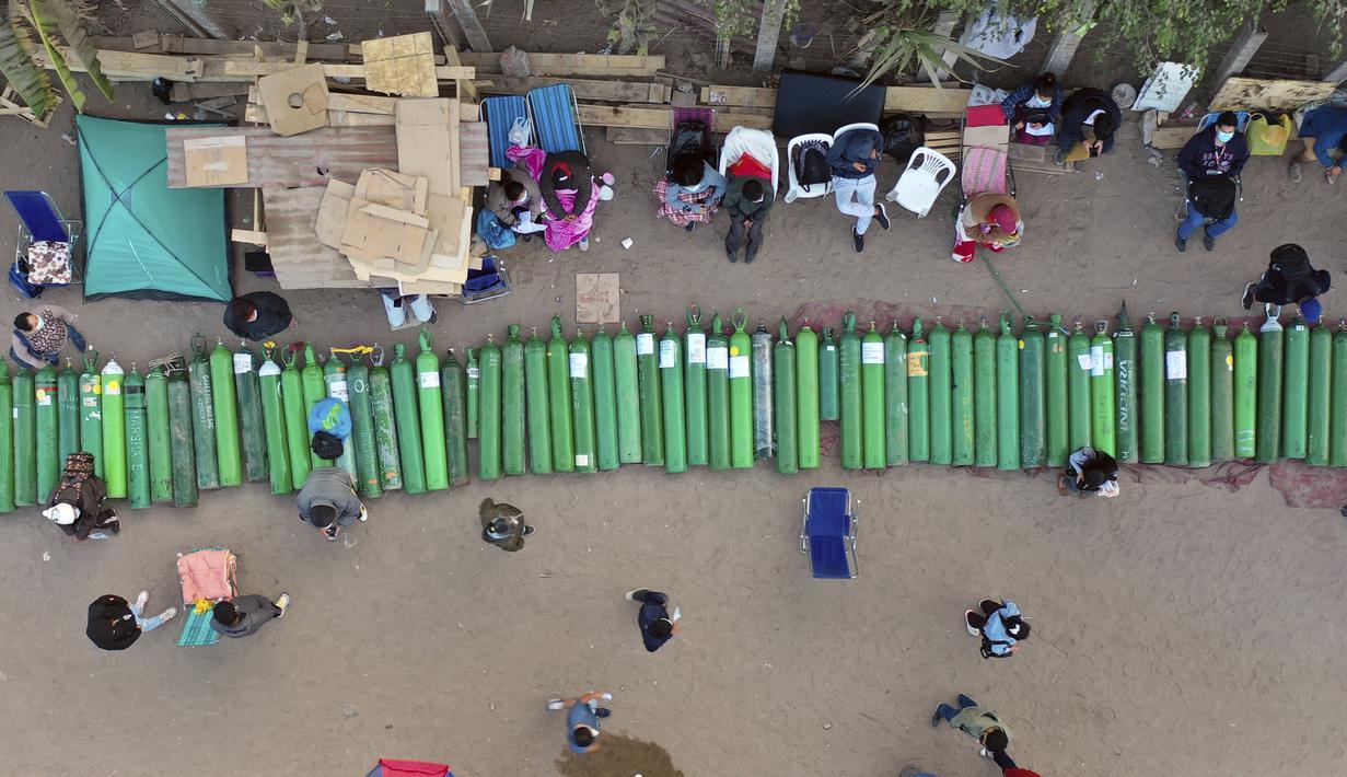 Lusinan tabung oksigen kosong tergeletak di jalan ketika orang-orang menunggu toko buka untuk mengisi tabung mereka di Villa El Salvador, Lima, Peru, Selasa (6/4/2021). Warga Peru terus berjuang mendapatkan oksigen medis untuk merawat pasien COVID-19. (AP Photo/Rodrigo Abd)
