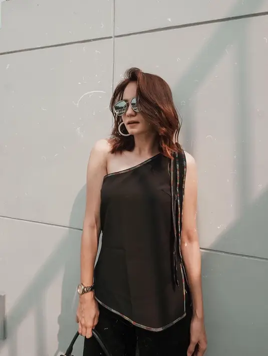Menggunakan outfit one shoulder berwarna hitam, gaya Enzy Storia satu ini tampil begitu chic. Ia juga menambahkan kacamata hitam serta anting dan jam tangan untuk membuat gaya penampilannya semakin menawan. (Liputan6.com/IG/@enzystoria)