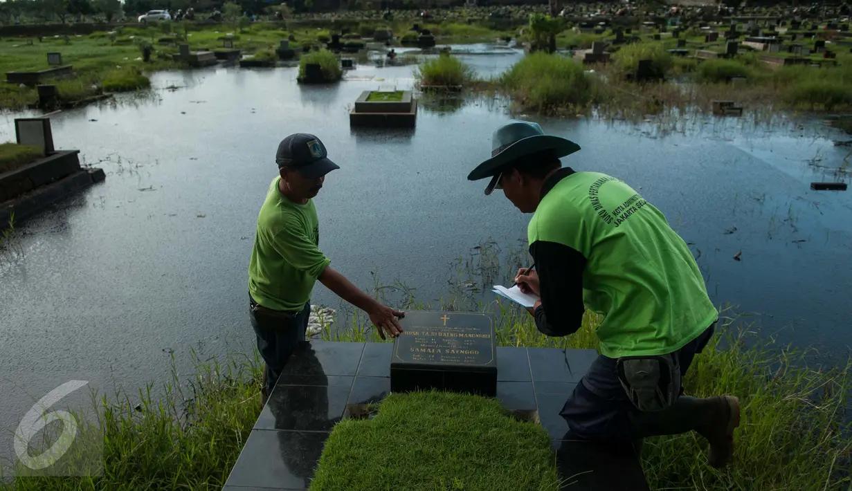Petugas mendata makam yang terendam di area Tempat Pemakaman Umum (TPU) Tanah Kusir, Jakarta, Selasa (25/4). (Liputan6.com/Gempur M. Surya)