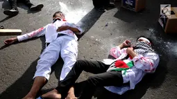 Peserta aksi melakukan teatrikal tentang kekejaman tentara Israel di kawasan Bundaran HI, Jakarta, Minggu (10/12). Mereka memprotes keputusan Presiden AS Donald Trump yang mengakui Yerusalem sebagai Ibu Kota Israel. (Liputan6.com/Helmi Fithriansyah)