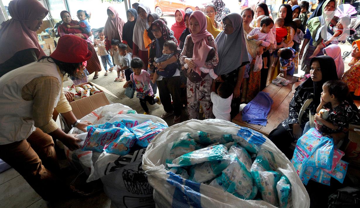 Warga antre mendapatkan pampers dan biskuit bagi anak-anak di Posko pengungsian Mangunkerta, Cianjur, Jumat (23/12/2022). Lebih dari sebulan sejak musibah gempa bumi 5,2 SR sejumlah warga masih tinggal di pengungsian dengan bantuan kebutuhan hidup dari para donatur. (merdeka.com/Arie Basuki)