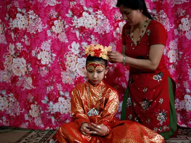 Dewi Hidup, Kumari Unikia Bajracharya (duduk) saat dirias oleh ibunya untuk menghadiri festival untuk Rato Machhindranath di Lalitpur, Nepal, Selasa (10/5). Kumari dianggap reinkarnasi dari dewi-dewi yang hidup di zaman dahulu. (REUTERS/Navesh Chitrakar)