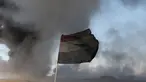 Sebuah bendera Irak terlihat di depan ladang minyak yang dibakar oleh ISIS di Qayyara, selatan Mosul, Irak, (23/11).Sebelumnya, sekitar enam sumur minyak telah dibakar ISIS di kawasan tersebut. (REUTERS/Goran Tomasevic)