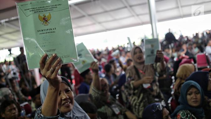 Warga menunjukkan sertifikat tanah yang baru diserahkan oleh Presiden Joko Widodo di Pusat Penerbangan Angkatan Darat, Pondok Cabe,  Tangsel, Jumat (25/1). Pada kesempatan ini, 40.172 sertifikat tanah dibagikan oleh Jokowi (Liputan6.com/Faizal Fanani)