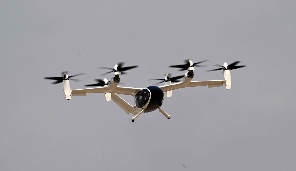Penerbangan ini menandai tonggak sejarah sebagai uji coba taksi udara titik-ke-titik (point-to-point) berawak pertama di Uni Emirat Arab (UEA). Tampak dalam foto, sebuah taksi udara listrik Joby melakukan uji terbang di Bandara Internasional Al-Maktoum selama Pameran Udara Dubai 2025 pada 17 November 2025. (Giuseppe CACACE/AFP)
