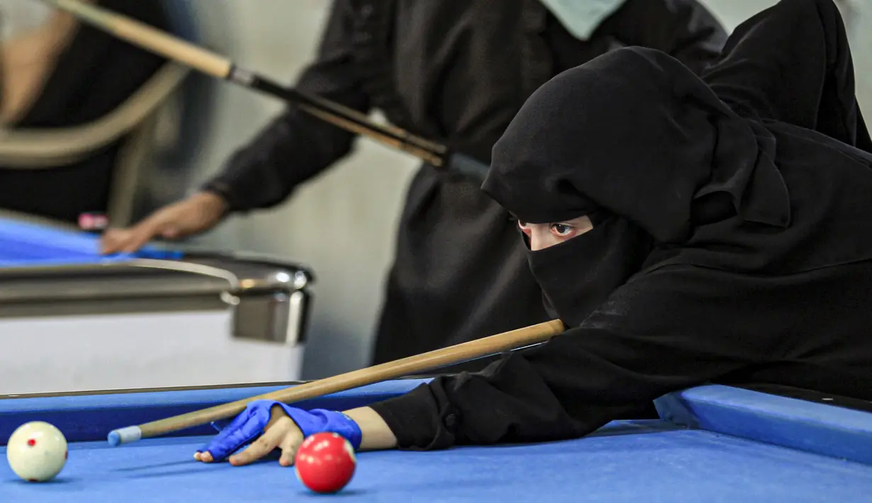 Seorang wanita membidik bola saat mengikuti kejuaraan biliar lokal di sebuah gedung olahraga di ibu kota  Sanaa, Yaman  (16/12/2019).  (AFP/Mohammed Huwais)