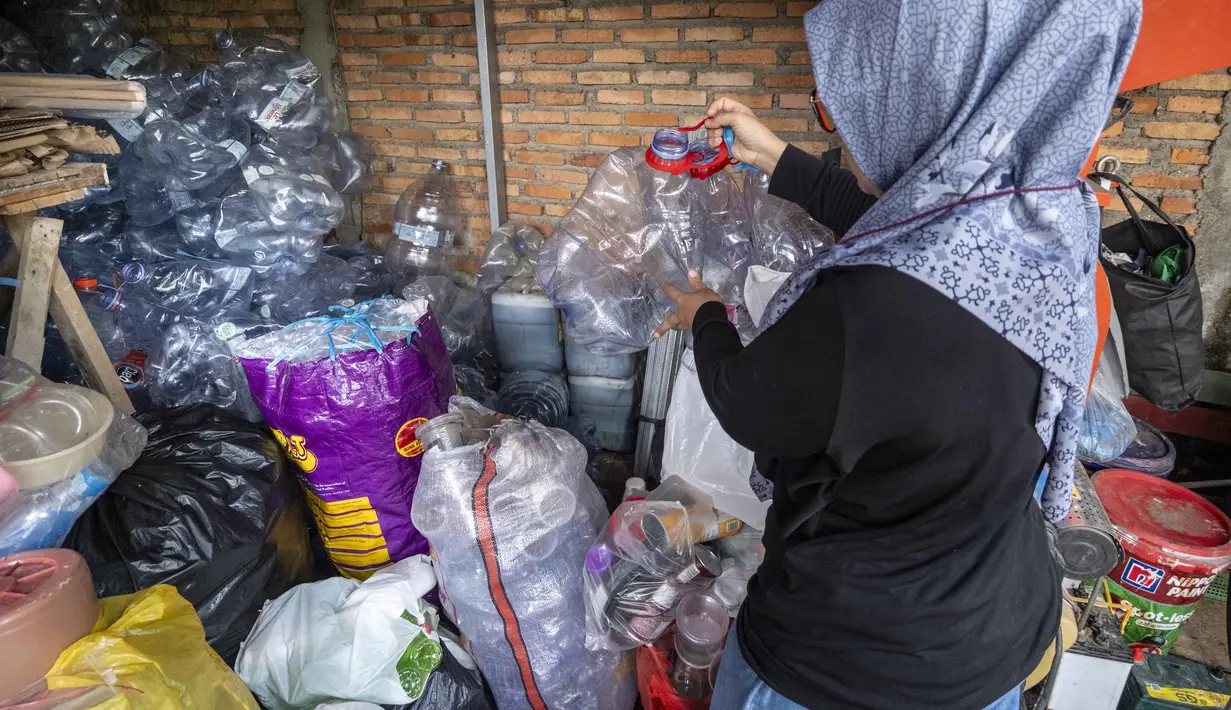 Seorang pegawai bank sampah memilah sampah anorganik rumah tangga, baik berupa karton maupun botol plastik, Jakarta, Kamis 4 Juni 2026, sebagai bagian dari instruksi Pemprov DKI yang mewajibkan warga memilih dan memilah sampah untuk mengurangi beban sampah yang semakin menumpuk di ibu kota. (BAY ISMOYO/AFP)
