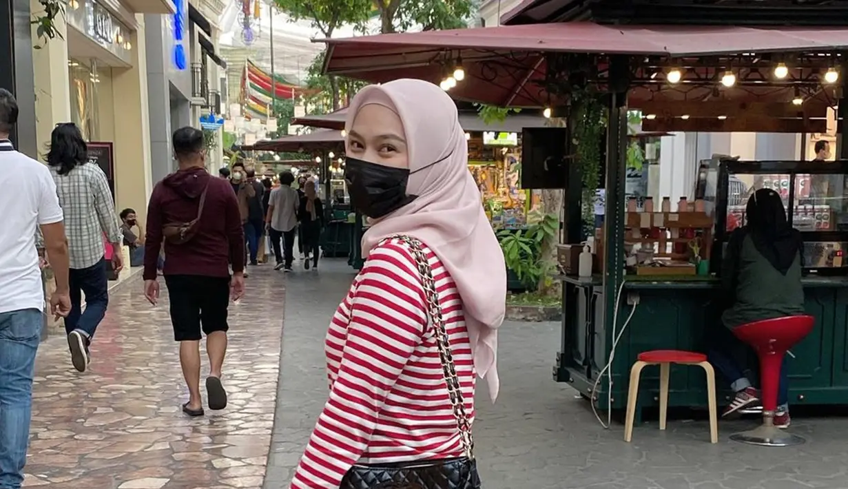 Pakai baju stripe warna merah dipadukan dengan hijab simpel dan celana warna hitam, penampilan sahabat Nabilah Eks JKT48 ini bak anak muda. Tas warna hitam yang senada dengan warna celananya menambah kesan elegan dari penampilan penyanyi yang bergabung dengan JKT48 sejak tahun 2011 ini. (Liputan6.com/IG/@melodylaksani92)