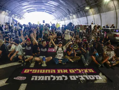 Keluarga dan pendukung warga Israel yang disandera oleh militan Hamas di Gaza sejak serangan pada 7 Oktober 2023, meneriakkan slogan-slogan saat mereka memblokir arus lalu lintas di sebuah terowongan di Yerusalem pada 17 Agustus 2025. (Menahem Kahana/AFP)