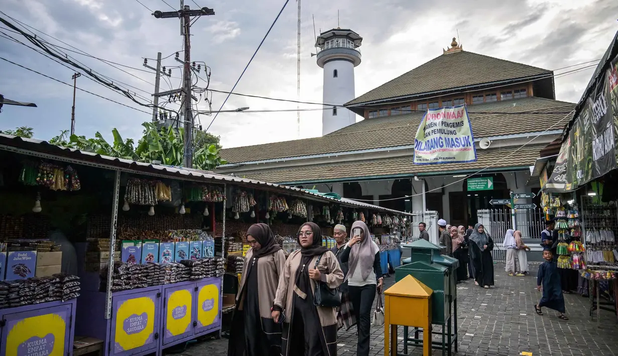 Sore menjelang waktu berbuka, kawasan ini ramai dikunjungi warga dan sejumlah pedagang pakaian/makanan beroperasi hingga 24 jam. Tampak dalam foto, warga berjalan saat bulan suci Ramadan di sekitar Masjid Sunan Ampel, Surabaya, Jawa Timur, pada Minggu 8 Maret 2026. (JUNI KRISWANTO/AFP)