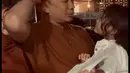 Setelah pakai rambut palsu alias wig, Kama baru mau di gendong oleh ayahnya. "Inilah saya harus pakai wig," kata Hanung sambil mengedong dan mencium anak bontotnya. [Instagram/hanungbramantyo]