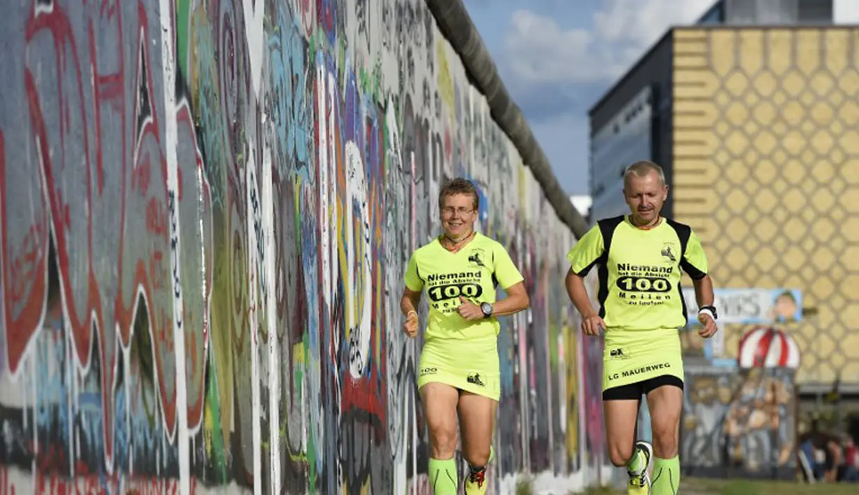 Martina Schliep (kiri) dan Gaston Pruefer berlari di sisi timur Tembok Berlin, Jerman, (11/8/2014). (AFP PHOTO/Tobias Schwarz)