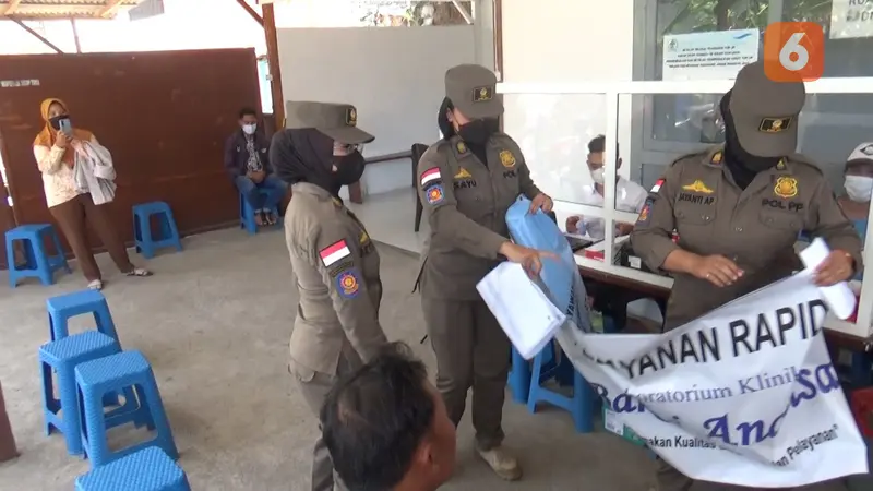 Satpol PP Banyuwangi Menurutkan Papan Nama Gerai Rapid Test Antigen Tidak Berijin. (Hermawan Arifianto/Liputan6.com)