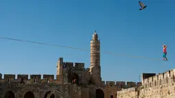 Slackliner Amerika, Heather Larsen saat beraksi melintasi dua menara Museum David di Yerusalem 2 Mei 2016. Slackline merupakan olahraga untuk melatih keseimbangan diatas seutas tali yang dibentangkan dengan berbagai macam ketinggian. (REUTERS / Nir Elias)