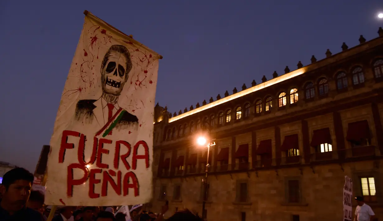Pengunjuk rasa mengangkat poster tengkorak Presiden Enrique Pena Nieto saat demonstrasi menolak kenaikan harga BBM, Mexico City, Meksiko (9/1). Akibat kenaikan BBM, sebagian warga nekat melakukan aksi vandalisme hingga penjarahan. (AFP/Alfredo Estrella)