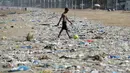 Seorang pria berjalan mengiring bola di pantai Juhu yang dipenuhi sampah plastik di Mumbai, India (2/6). (AFP PHoto/Punit Paranjpe)