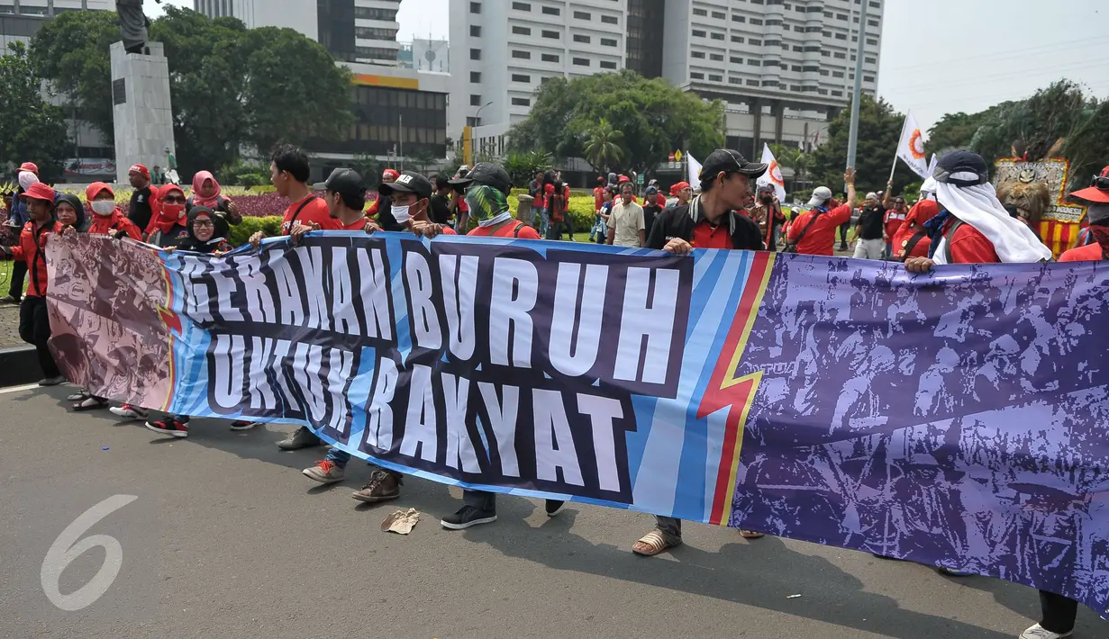 Massa aksi Hari Buruh membawa spanduk saat memperingati Hari Buruh Internasional di Jakarta, Senin (1/5). Dalam aksinya para buruh meminta sistem kerja kontrak dan upah rendah dihapus. (Liputan6.com/Helmi Afandi)