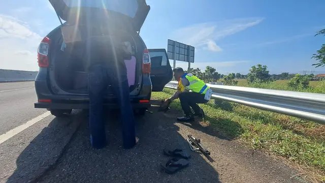 Polisi bantu mengganti ban mobil pemudik yang pecah di Tol Pemalang-Batang. (Foto: Liputan6.com/Polres Pemalang)