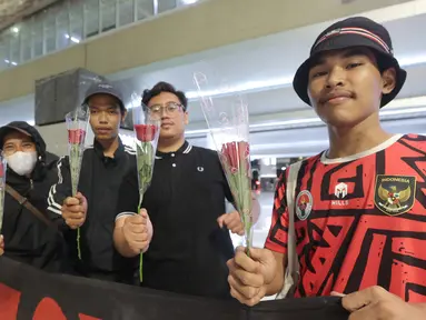 Suporter menunjukkan bunga yang akan diberikan kepada para pemain Timnas Futsal Indonesia yang tiba di Bandara Soekarno-Hatta, Tangerang, Senin (11/11/2024). (Bola.com/M Iqbal Ichsan)